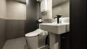 Une salle de bain moderne équipée de toilettes, d’un lavabo et d’un espace douche.