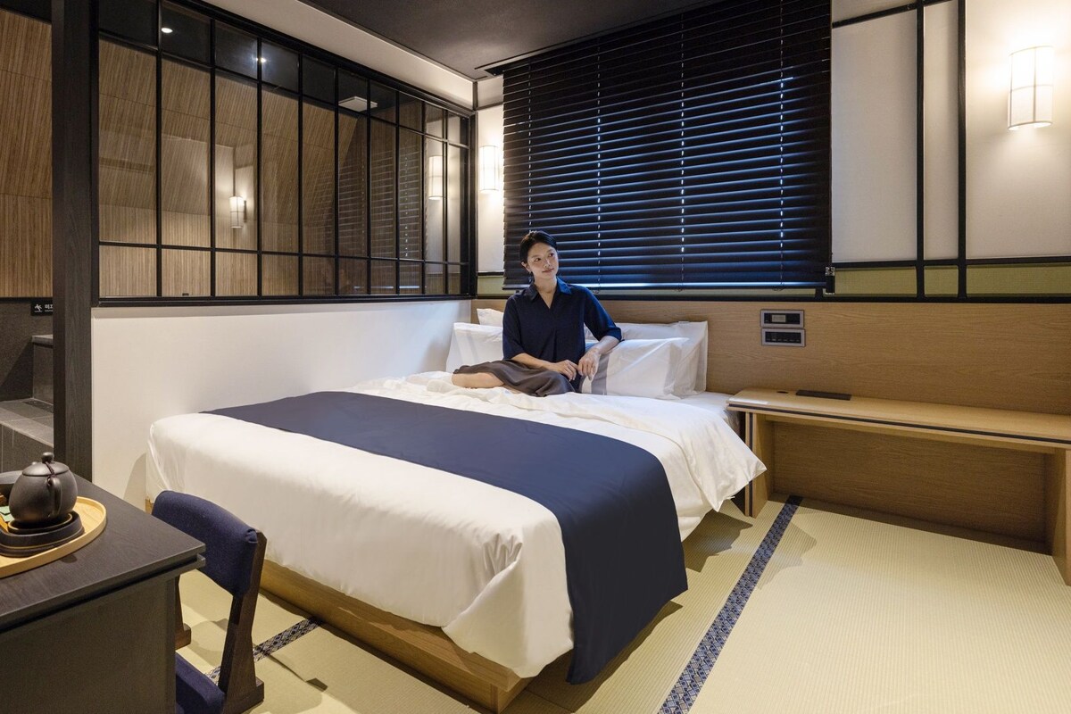 Une chambre d’hôtel équipée d’un lit, d’une table de chevet et d’un bureau avec une bouilloire.