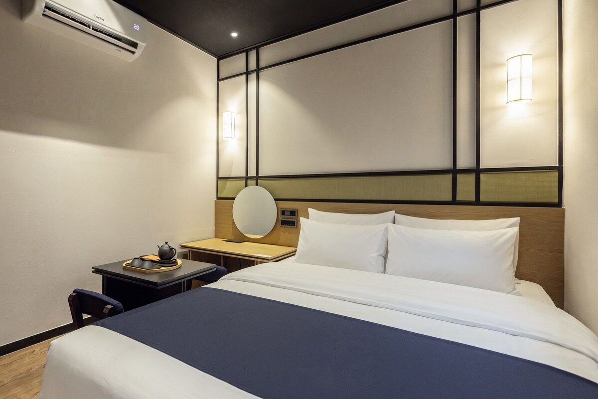 Une chambre d’hôtel équipée d’un lit, d’une table de chevet, d’une lampe et d’un appareil de climatisation.