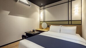 Une chambre d’hôtel équipée d’un lit, d’une table de chevet, d’une lampe et d’un appareil de climatisation.