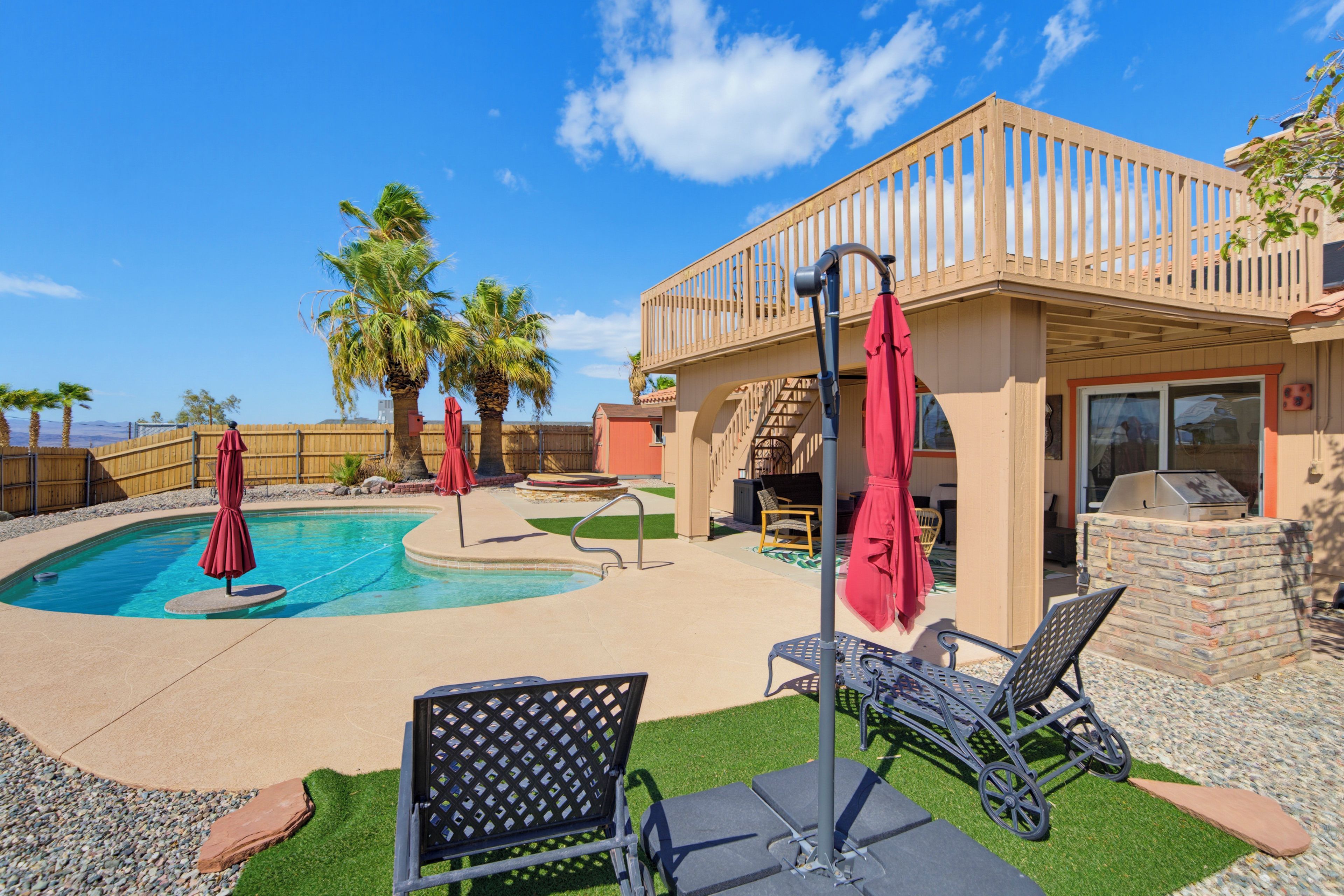 A backyard with a swimming pool, lounge chairs, and a covered patio area.