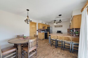 A kitchen with wooden cabinets, a dining table with chairs, and a ceiling fan. - Tranquil Lake Havasu Getaway - Private Pool - Rooftop Patio (Lake Havasu City)