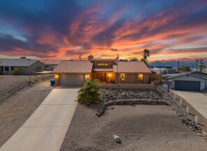 A two-story house with a tiled roof, a driveway, and a landscaped front yard with rocks and a small bush. - Tranquil Lake Havasu Getaway - Private Pool - Rooftop Patio (Lake Havasu City)