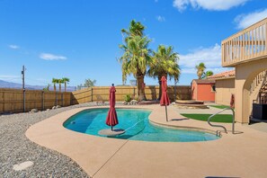 A swimming pool with a wooden deck, palm trees, and a fenced area. - Tranquil Lake Havasu Getaway - Private Pool - Rooftop Patio (Lake Havasu City)