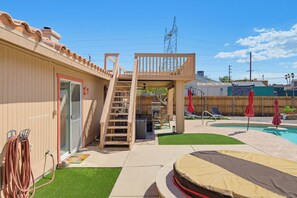 Un jardin avec une piscine, une terrasse en bois et un espace patio couvert.
