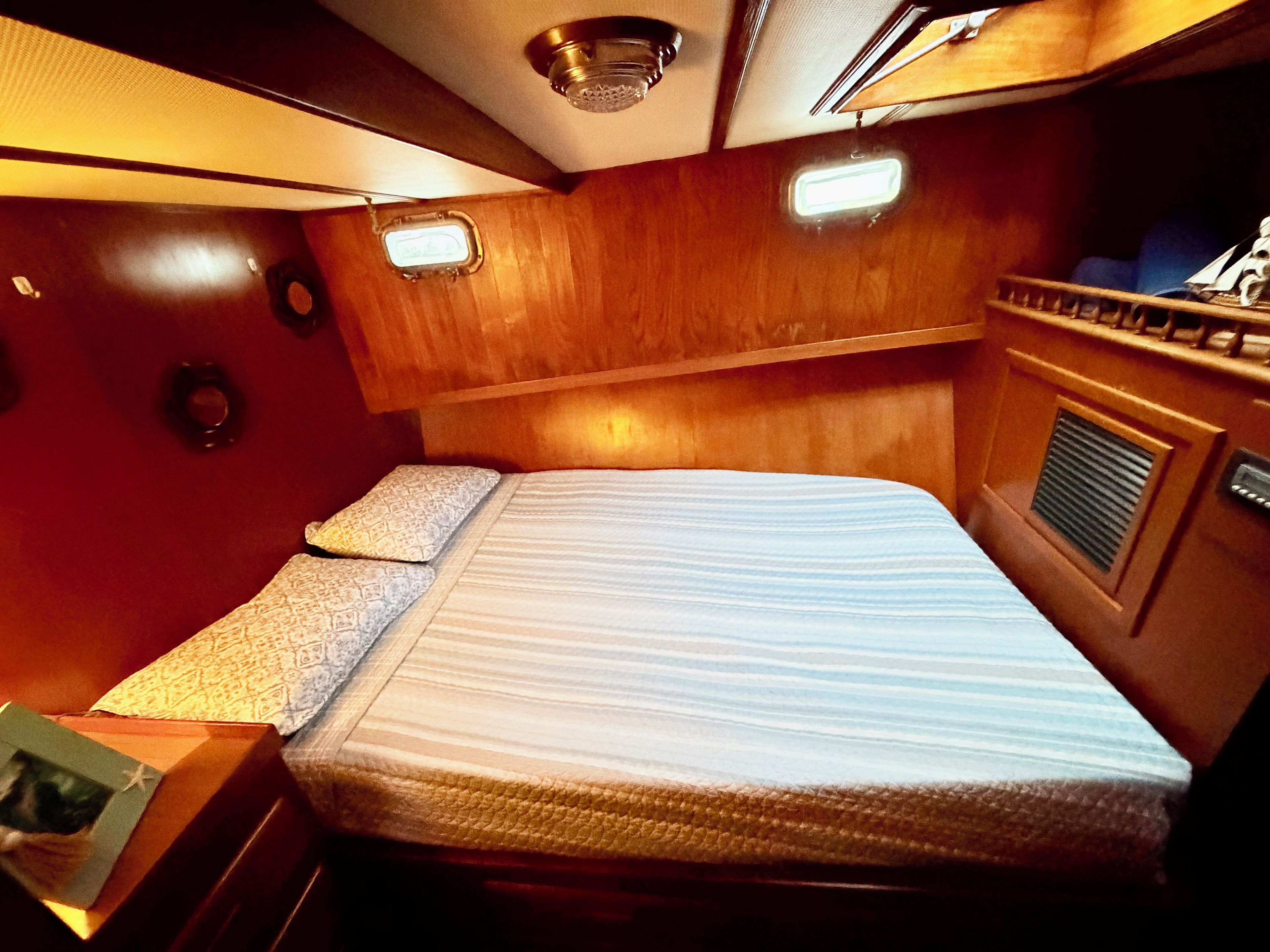 Une petite cabine comprenant un lit simple, une petite table et une tête de lit.