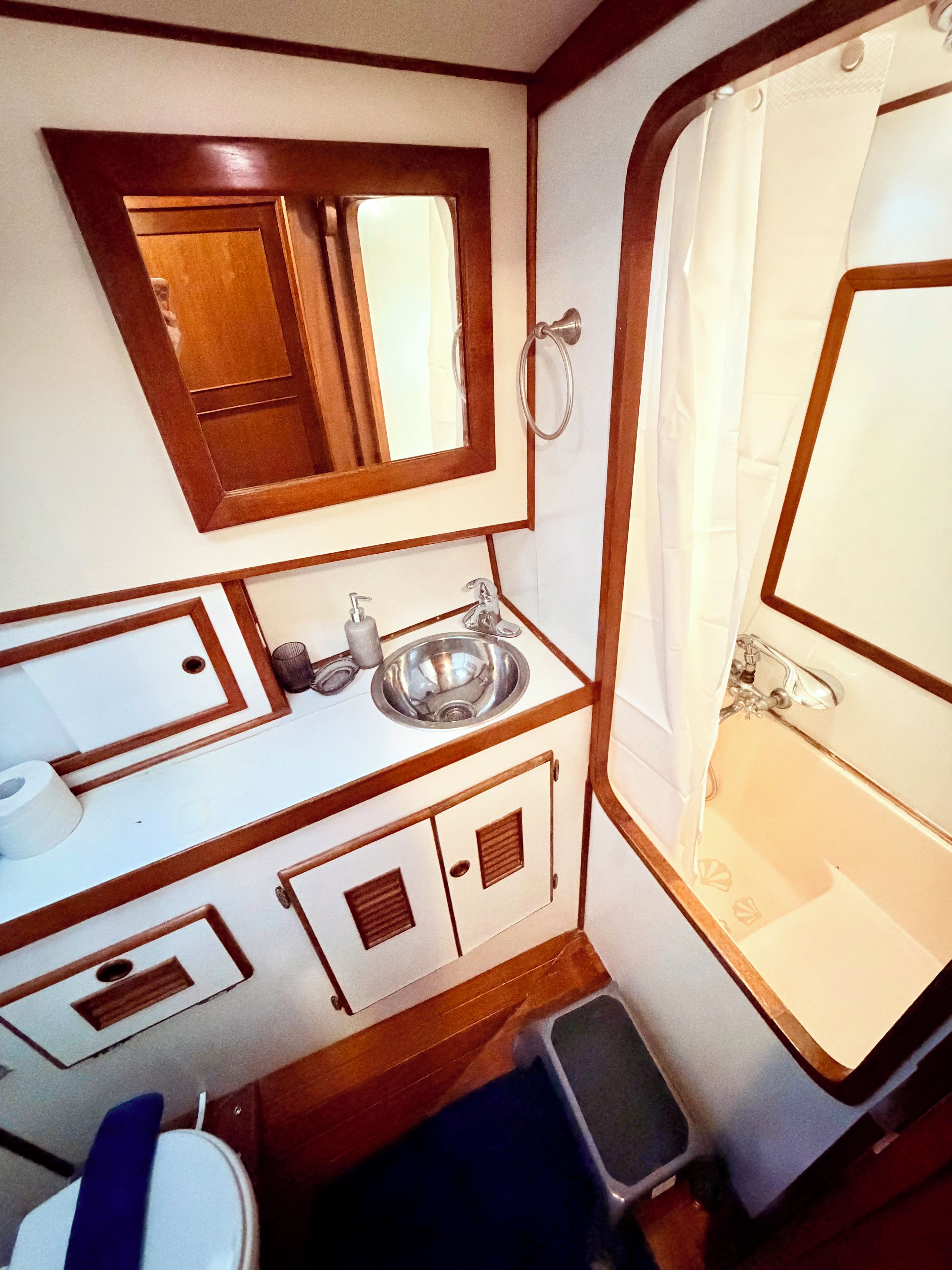 Une petite salle de bain avec un meuble-lavabo en bois, un évier, un miroir et un espace douche.