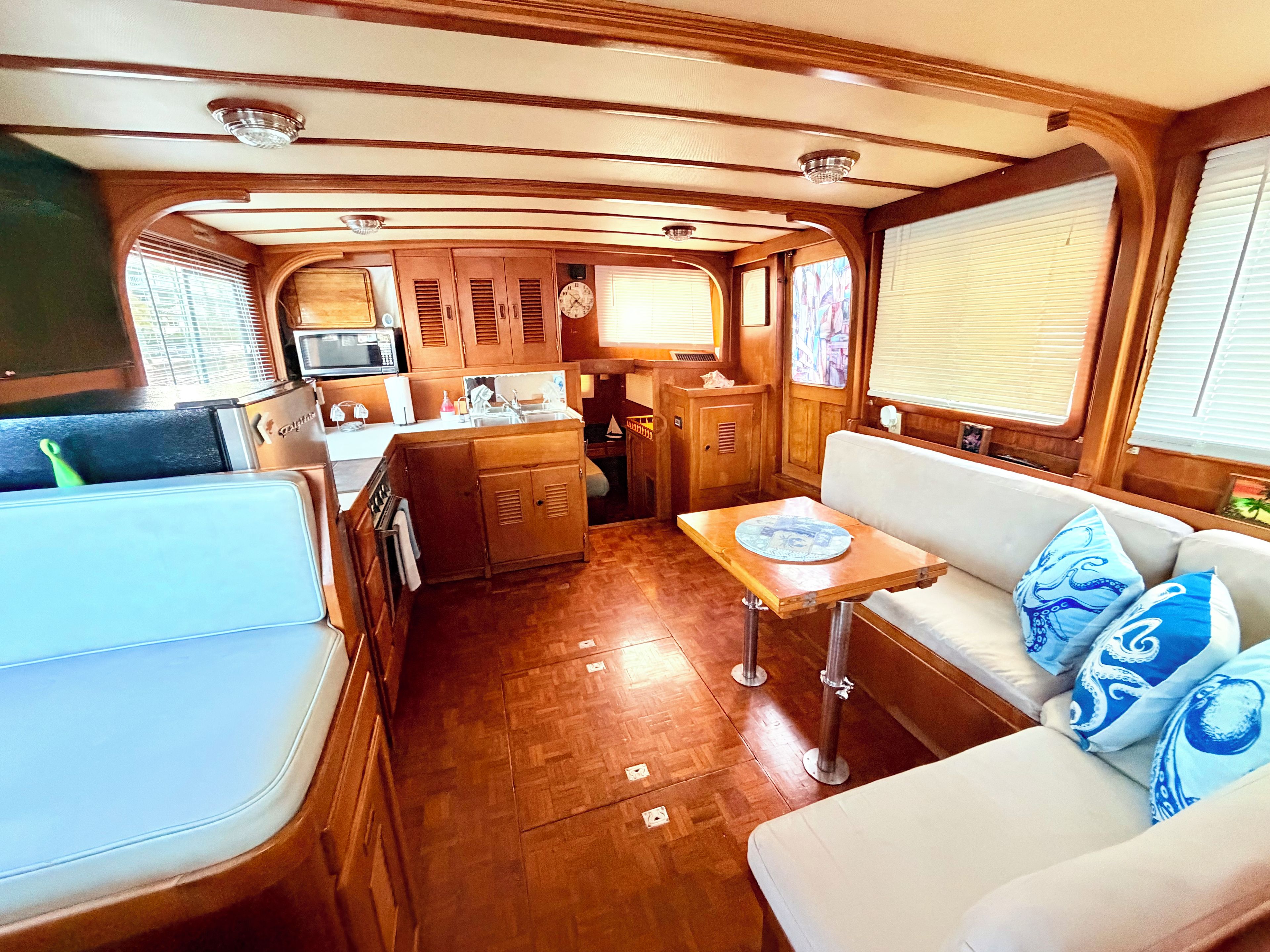 Een ruimtelijk RV-interieur met een kitchenette, een eethoek en een zithoek met kussens.