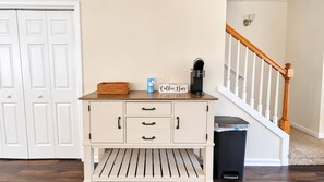 A kitchenette with a coffee maker, a basket, and a trash bin. - The Happy Habitat (Clarksville)