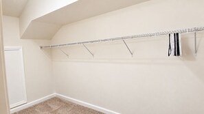 A closet with a metal rod and hooks, a white door, and a carpeted floor. - The Happy Habitat (Clarksville)