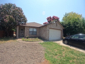 A single-story house with a garage, a driveway, and a black car parked in front. - Cozy San Riveria Pool property near Sea World 3bed 2bath house with fireplace! (San Antonio)