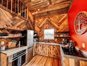 A kitchen with wooden herringbone flooring, a central island with a sink, and a hanging light fixture. - 9 Properties on Entire Farm (Indianapolis)
