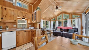 Ein Holzblockhaus-Interieur mit Küche, Essbereich und Wohnzimmer.