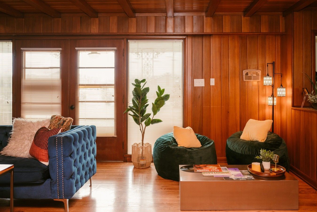 A cozy living room with a blue sofa, green bean bag, and a coffee table with magazines.