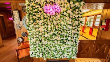 A wall covered with white flowers and a neon sign that reads 'You're like I'm really pretty.'