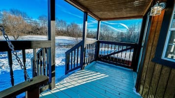 Une terrasse en bois avec une rambarde, une lanterne et une vue sur un paysage enneigé.