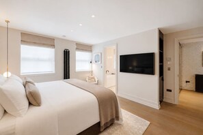 A modern bedroom with a large bed, a flat-screen TV, and a fireplace. - Mayfair Duplex Private Terrace AC (London)