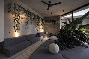 A modern interior with a built-in bench, a ceiling fan, and a large plant. - Predmet KabaKaba Resort (Tabanan)