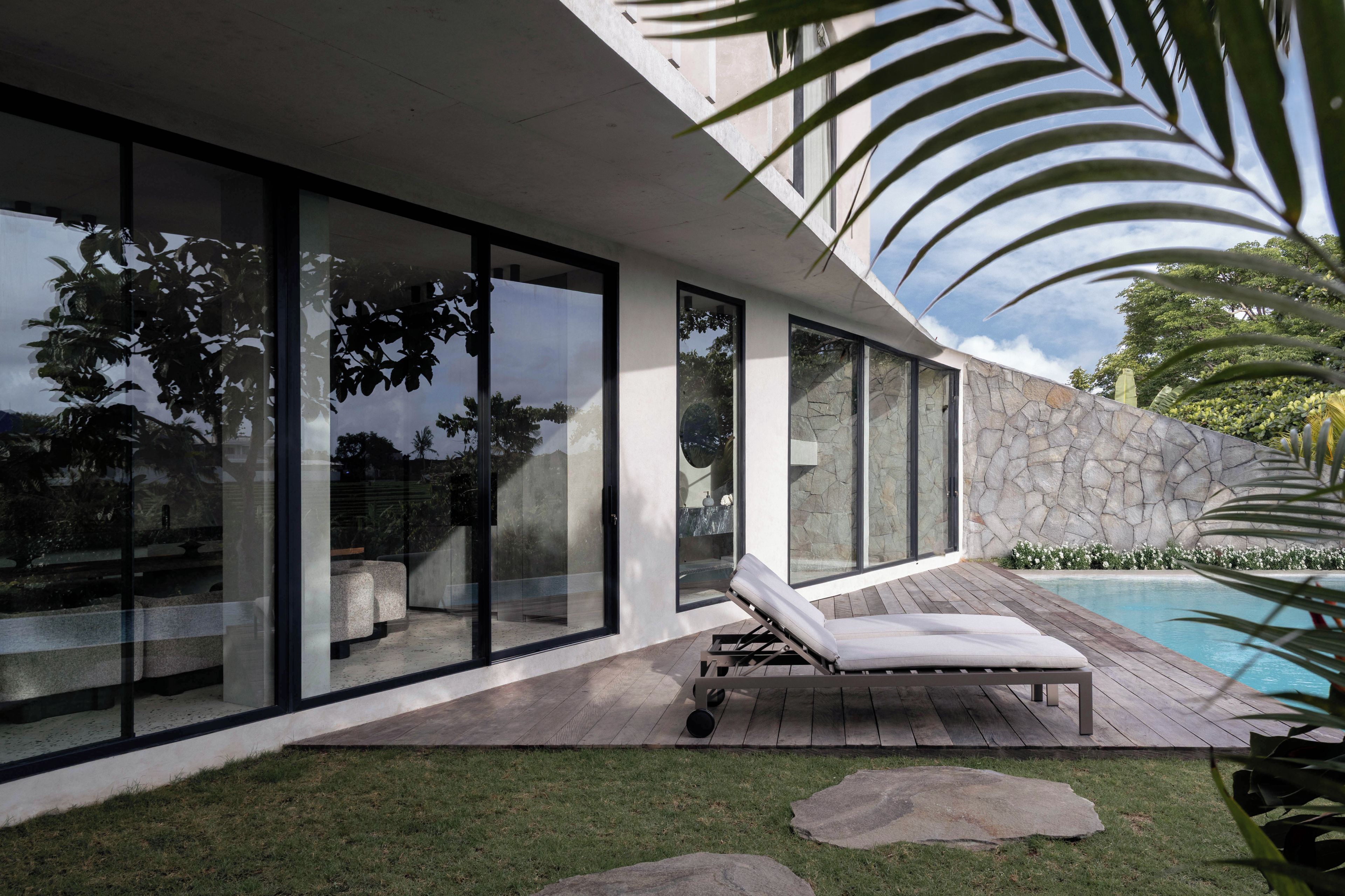 A modern house with large glass windows, a wooden deck, and a swimming pool.