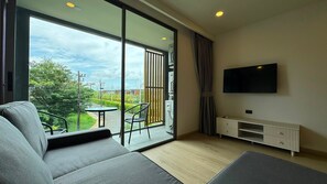 A modern living room with a sofa, a television, and a balcony with a table and chairs. - Modern 2 Bed, 2 Bath in Bang Tao - Brand New 75sqm at Ozone (Choeng Thale)