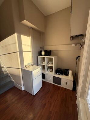 A compact kitchen with a refrigerator, microwave, and a coffee maker on a shelf. - Sunny 2-bed Triplex With Private Terrace (London)