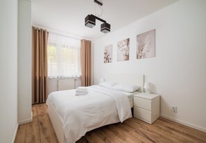A bedroom with a bed, bedside table, and wall-mounted artwork. - Praga Południe Harmony Apartment (Warszawa)