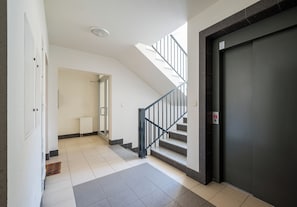 A hallway with a staircase, a radiator, and a door. - Praga Południe Harmony Apartment (Warszawa)