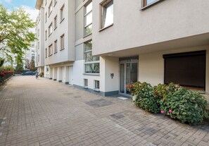 Un edificio moderno con un sendero pavimentado, una entrada porticada y una puerta con un letrero de seguridad.