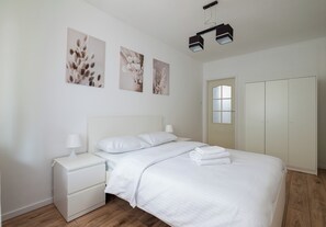 Een slaapkamer met een bed, nachtkastje en een kledingkast.