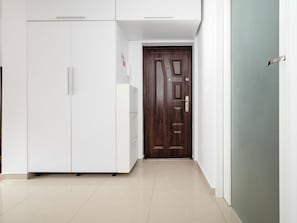 Un corridoio con un armadio bianco, una porta in legno e un muro verde.