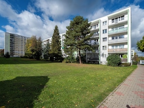 Un edificio residenziale a più piani con balconi, un'area verde e alberi.
