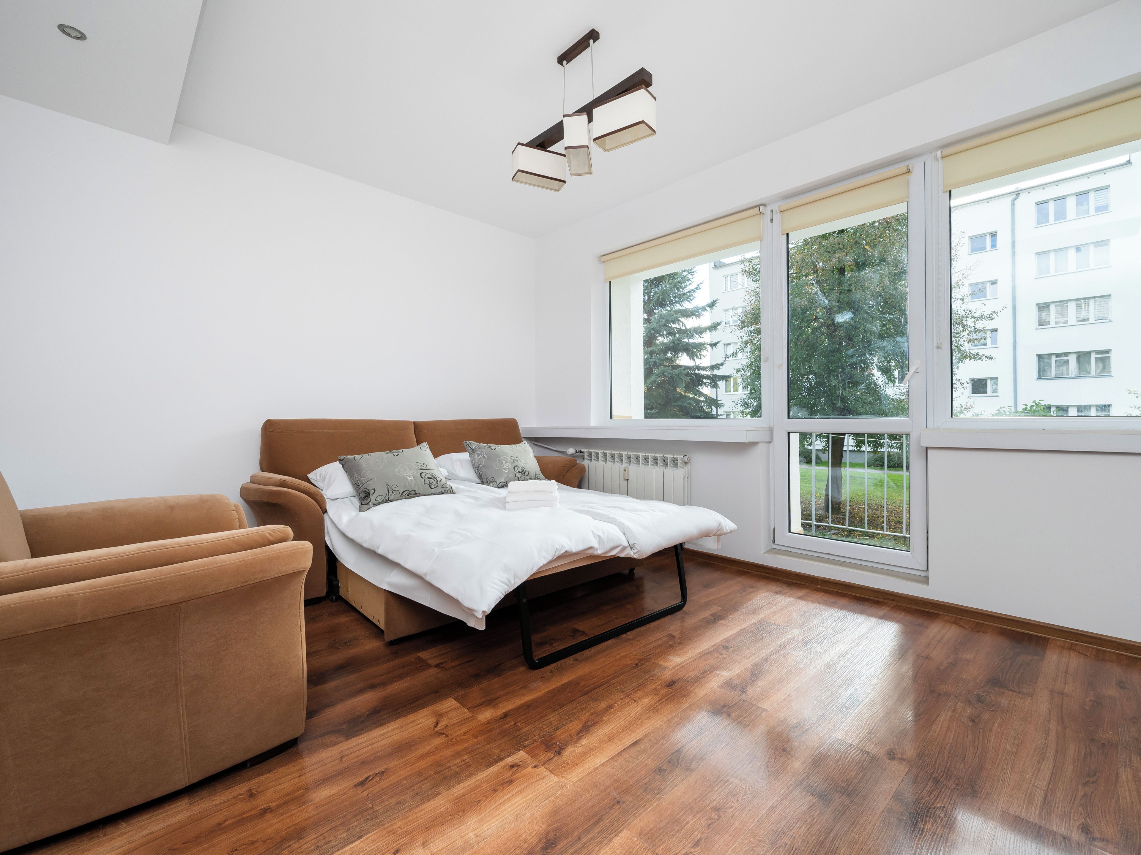 Een moderne slaapkamer met een bed, een slaapbank en grote ramen.