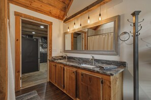 A modern kitchen with wooden cabinets, a granite countertop, and a large mirror above the sink. - Dual Blue Ridge Cabins, sleeps 14, large yard, dogs welcome! (Blue Ridge)