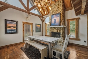 A rustic interior with a stone fireplace, wooden beams, and a dining area with a bench. - Dual Blue Ridge Cabins, sleeps 14, large yard, dogs welcome! (Blue Ridge)