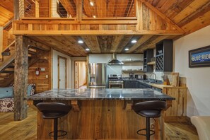A rustic kitchen with a wooden ceiling, a central island with bar stools, and a sign reading 'BLUE RIDGE Georgia'. - Dual Blue Ridge Cabins, sleeps 14, large yard, dogs welcome! (Blue Ridge)