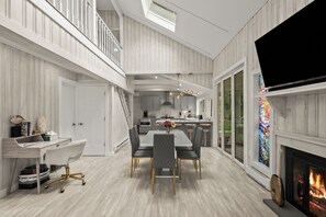 A spacious living area with a dining table, chairs, a fireplace, and a kitchen in the background. - Lakeshore Retreat-Modern Lakefront Home w/ Hot Tub (Monticello)