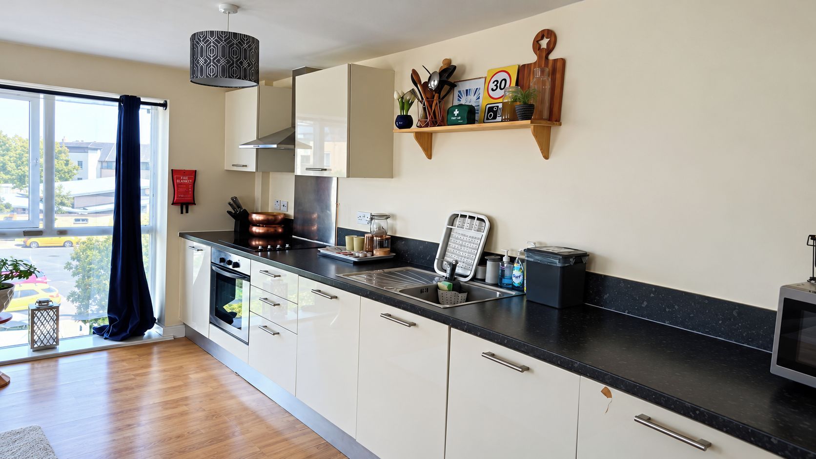 A modern kitchen with a large window, stainless steel appliances, and a black countertop.