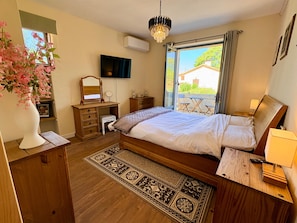 A bedroom with a bed, dresser, vanity, and a television. - Beautiful 3-Bed Stone Barn - Access to Blue Flag Lake (Lougratte)
