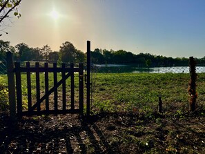 A wooden gate leading to a grassy field with a body of water in the background. - Beautiful 3-Bed Stone Barn - Access to Blue Flag Lake (Lougratte)