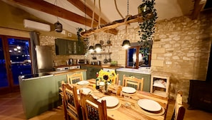 A rustic kitchen with stone walls, wooden beams, and a dining area with a table set for four. - Beautiful 3-Bed Stone Barn - Access to Blue Flag Lake (Lougratte)