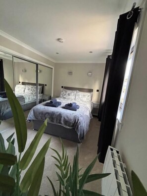 A bedroom with a bed, a mirror, a radiator, and a plant. - House Sleeps 4 with Enclosed Garden (Oban)