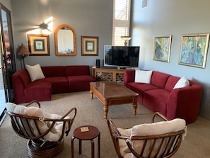 A living room with a red sectional sofa, two wooden chairs, a coffee table, and a television. - Wailea Ekahi 21D top floor ocean view 1bedroom 2bath short level walk to beach! (Kihei)