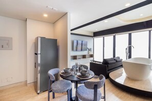 A modern kitchen with a built-in refrigerator, a dining area with a round table and chairs, and a large bathtub in a separate room. - Casa Myla a pasos de Polanco y Reforma (Mexico City)