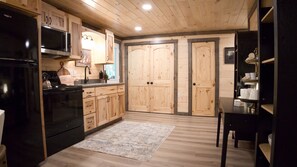 Eine Küche mit Holzausstattung, einem schwarzen Kühlschrank, einem Herd und einer Spüle.