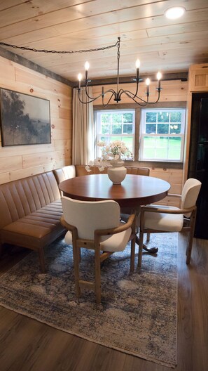Een eethoek met een houten tafel, stoelen, een bank en een kroonluchter.