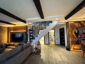 A modern living room with a staircase, a flat-screen TV, and a wooden floor. - 7-bedroom Villa Kazbegi-perfect for groups and families (Kazbegi)