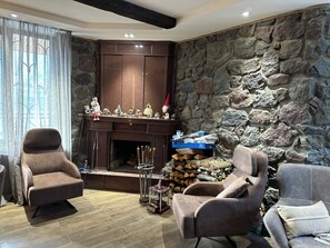 Ein gemütliches Wohnzimmer mit Steinwand, Kamin und zwei Sesseln.