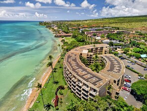 A coastal hotel with a curved building, a beach, and a view of the ocean. - Tropical Beach Oasis | Private Pool, Hot Tub & AC (Lahaina)