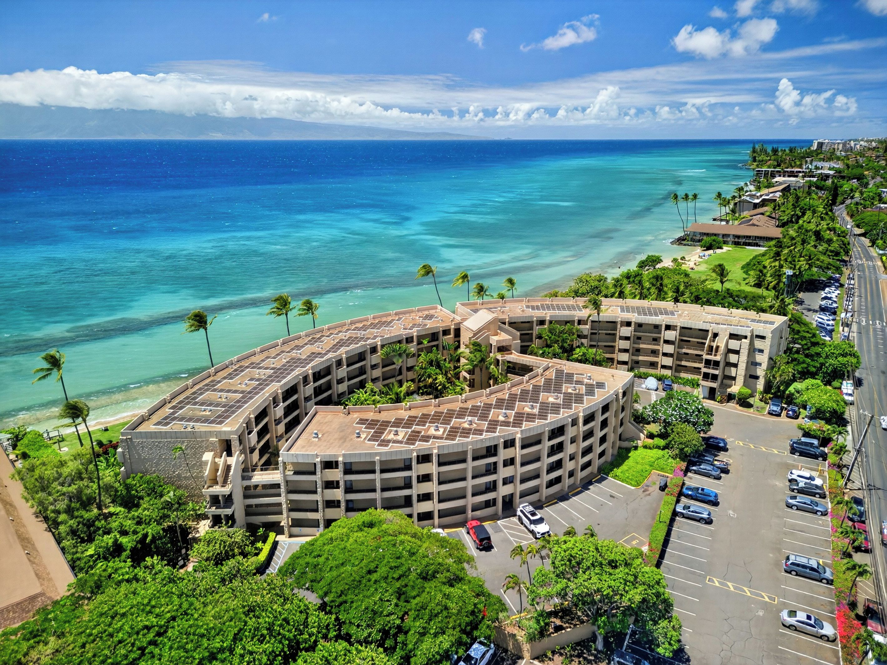 A multi-story parking structure with a curved roof, adjacent to a beachfront hotel with a view of the ocean.
