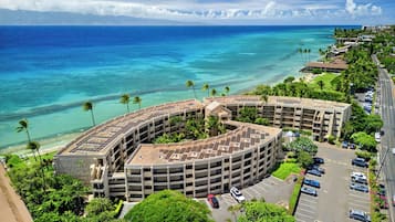A multi-story parking structure with a curved roof, adjacent to a beachfront hotel with a view of the ocean.